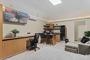Een moderne keuken met barstoelen, een eettafel en een aan de muur bevestigde televisie.