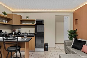 A compact kitchen with modern appliances, a dining area with a table and chairs, and a living area with a sofa and a plant. - Centro Histórico | Cochera | Mini split | Wifi (Durango)