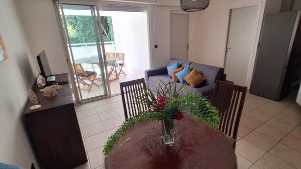 A living room with a dining table, a sofa, and a sliding glass door leading to a balcony. - Apartment T2 Fort-de-France quiet residential area. (Fort-de-France)