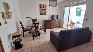 A living room with a sofa, a dining table with chairs, a TV on a cabinet, and a sliding glass door to a balcony. - Apartment T2 Fort-de-France quiet residential area. (Fort-de-France)