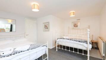 A bedroom with two single beds, a white door, and a radiator.