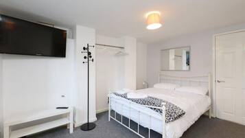 A bedroom with a bed, a wardrobe, a television, and a mirror.
