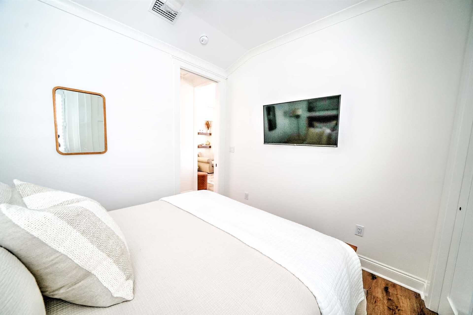 Un dormitorio con cama, espejo y un cuadro en la pared.