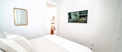 Un dormitorio con cama, espejo y un cuadro en la pared.