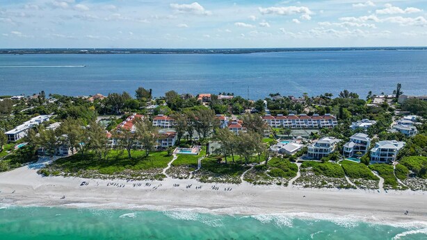 Un complejo turístico frente al mar con villas privadas, piscina y vistas al océano.