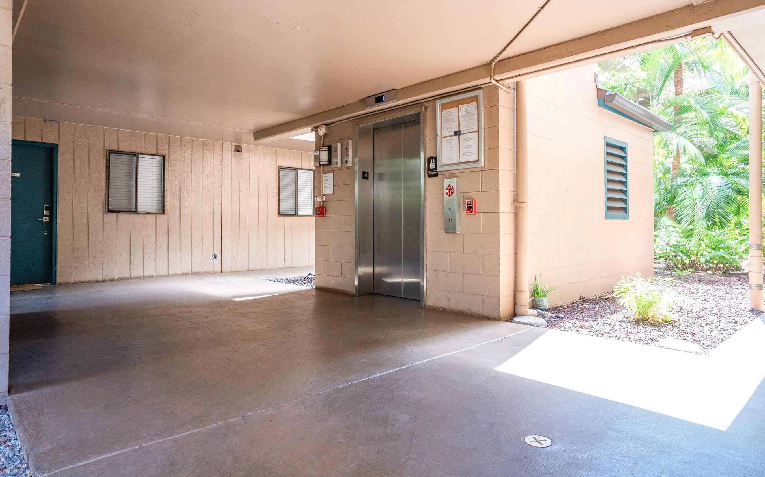 A building entrance with a concrete floor, a green door, and an elevator.