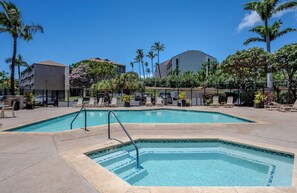 A swimming pool with a tiled edge, surrounded by lounge chairs and palm trees. - Pacific Shores B-409 - Beautifully Renovated Ocean View, 2 BD / 2 BA, Split AC! (Kihei)