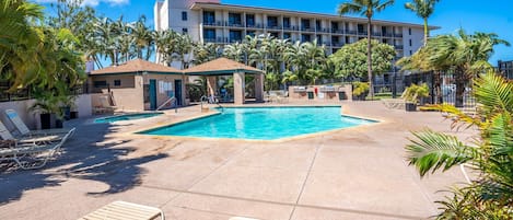 Et hotelområde med swimmingpool, liggestole, et overdækket loungeområde og en bygning med balkoner i baggrunden.