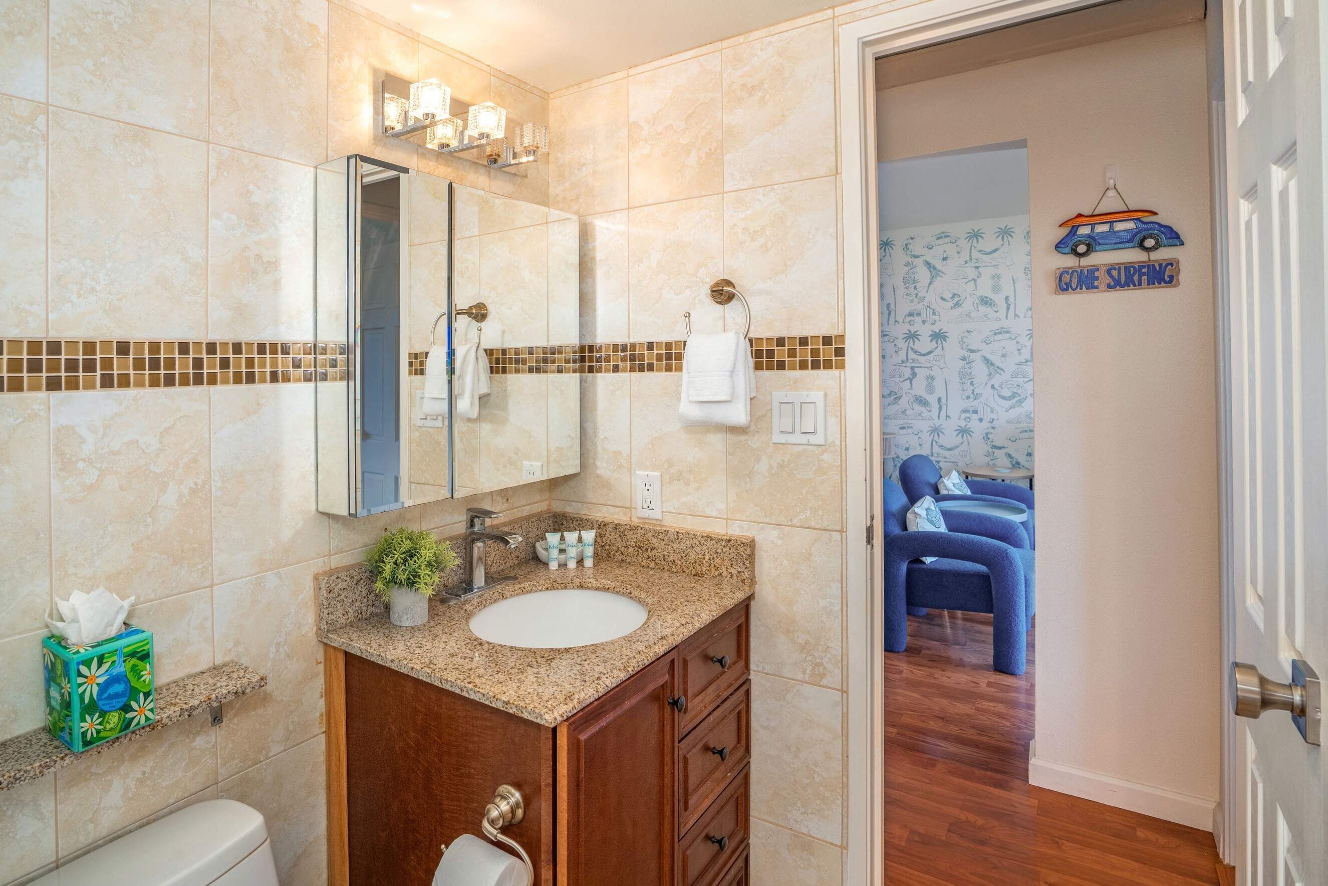 A bathroom with a vanity, sink, mirror, towel rack, and a door leading to a bedroom.
