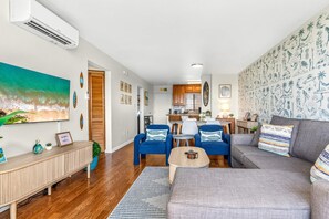 A modern living room with a sofa, chairs, and a dining area. There is a kitchen visible in the background. - Pacific Shores B-409 - Beautifully Renovated Ocean View, 2 BD / 2 BA, Split AC! (Kihei)