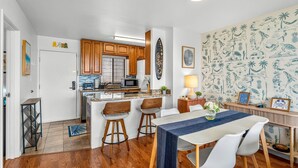Una cocina moderna con armarios de madera, una isla central y un comedor con mantel azul.