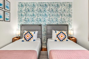A hotel room with two beds, a patterned headboard, and a nightstand with a lamp. - Pacific Shores B-409 - Beautifully Renovated Ocean View, 2 BD / 2 BA, Split AC! (Kihei)