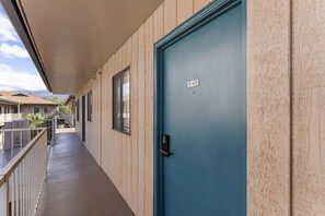 Un corridoio con una porta blu, una finestra e un balcone.