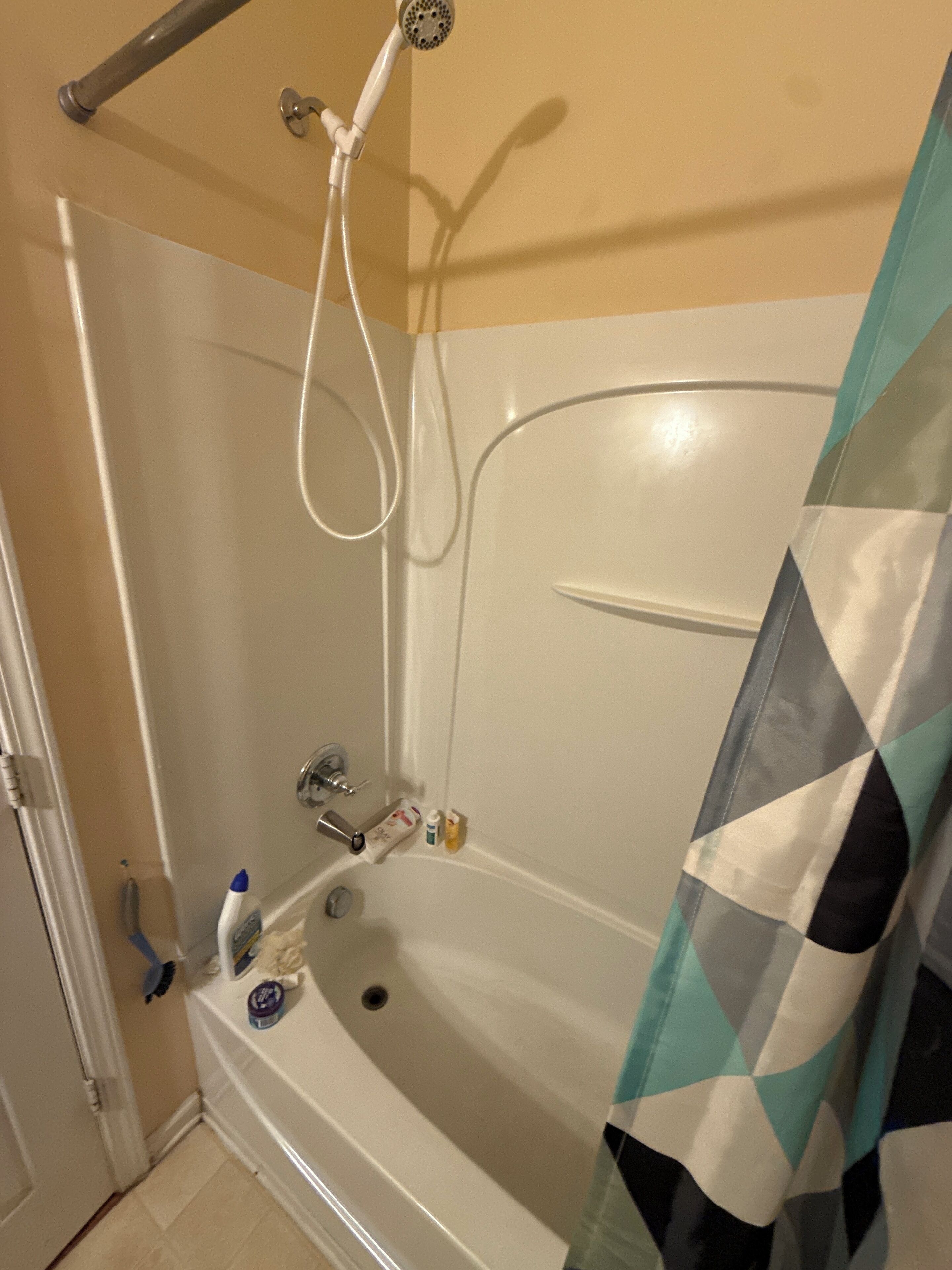 Et badeværelse med badekar, bruser og toilet.