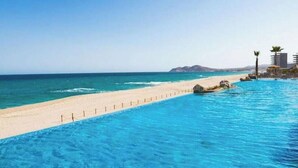 Una piscina cristallina con spiaggia sabbiosa e vista sull'oceano.