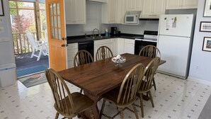 Una cucina con mobili bianchi, un tavolo da pranzo in legno e quattro sedie.
