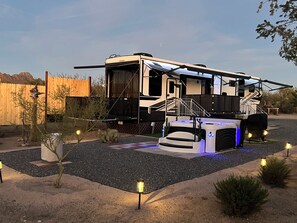 A large RV with a covered front area and a small attached vehicle.