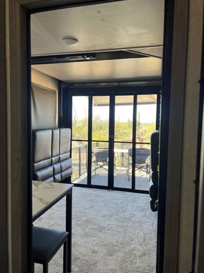 A room with a leather sofa, a small table, and a view of an outdoor patio with a table and chairs.