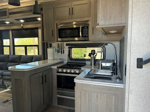 A compact RV kitchen with a built-in stove, oven, and microwave.