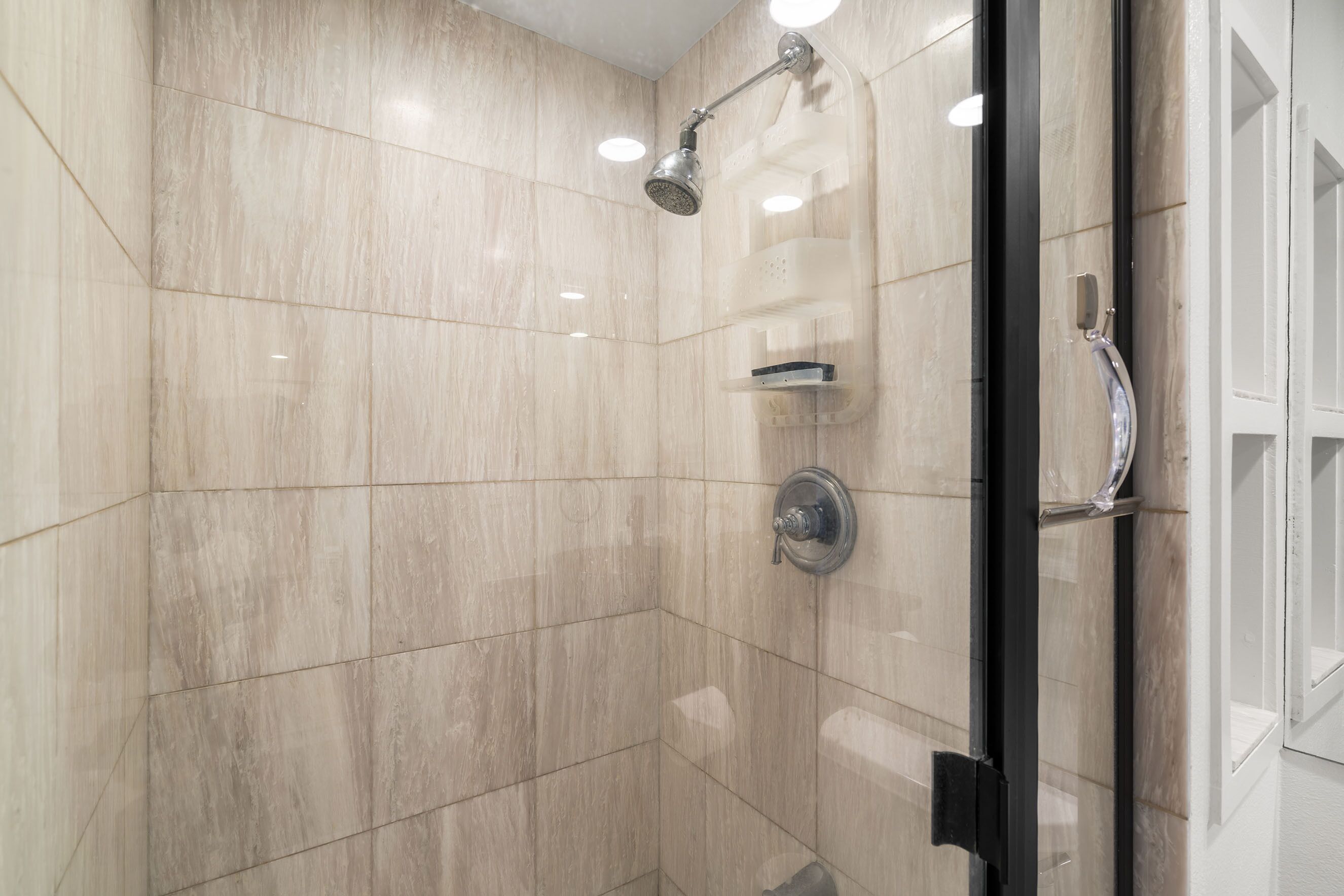 Een moderne douche met een handdouche en een wandmengkraan.