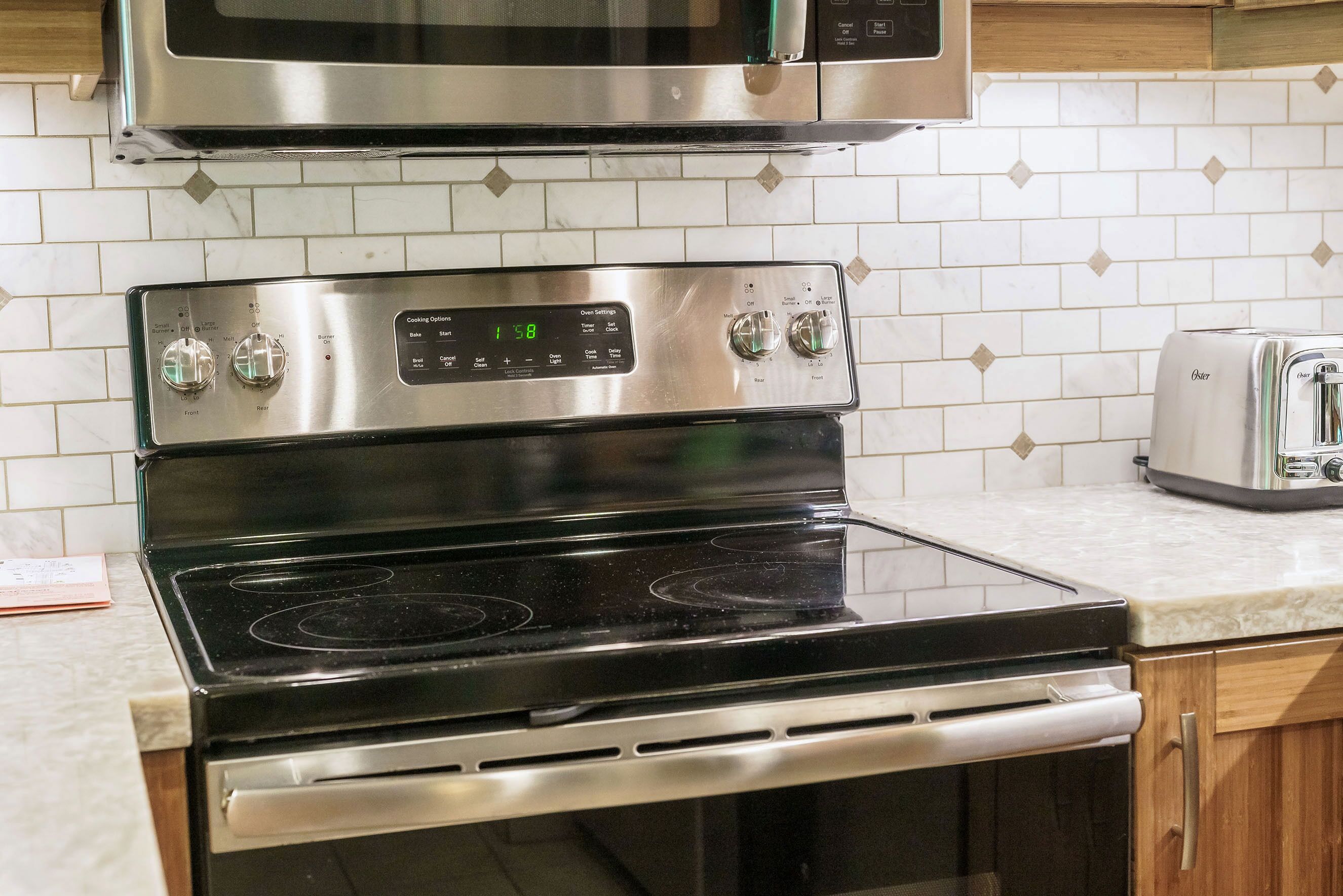 A kitchen with a stainless steel oven, a microwave above it, and a toaster on the countertop.