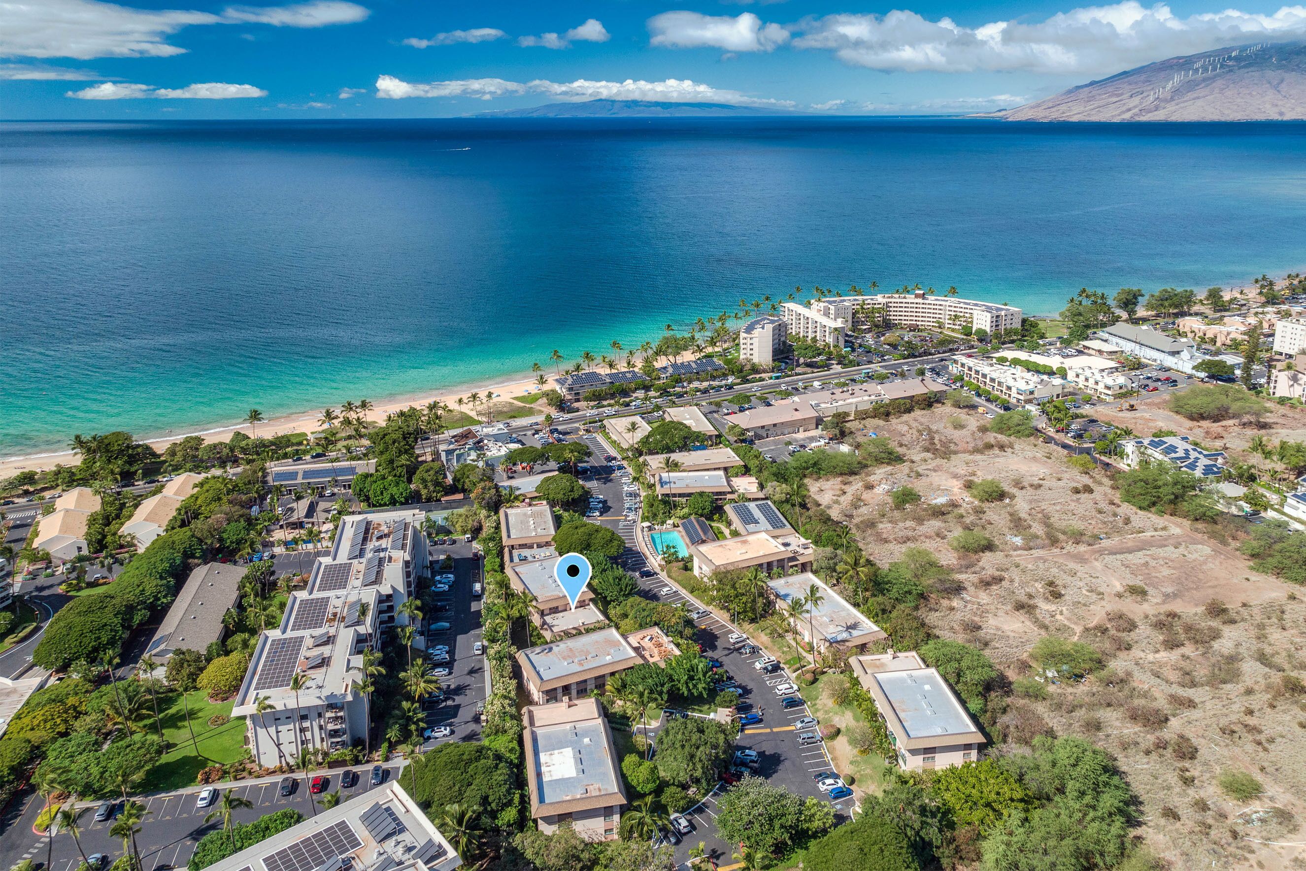 An aerial view of a coastal area with a beach, buildings, and a large body of water.