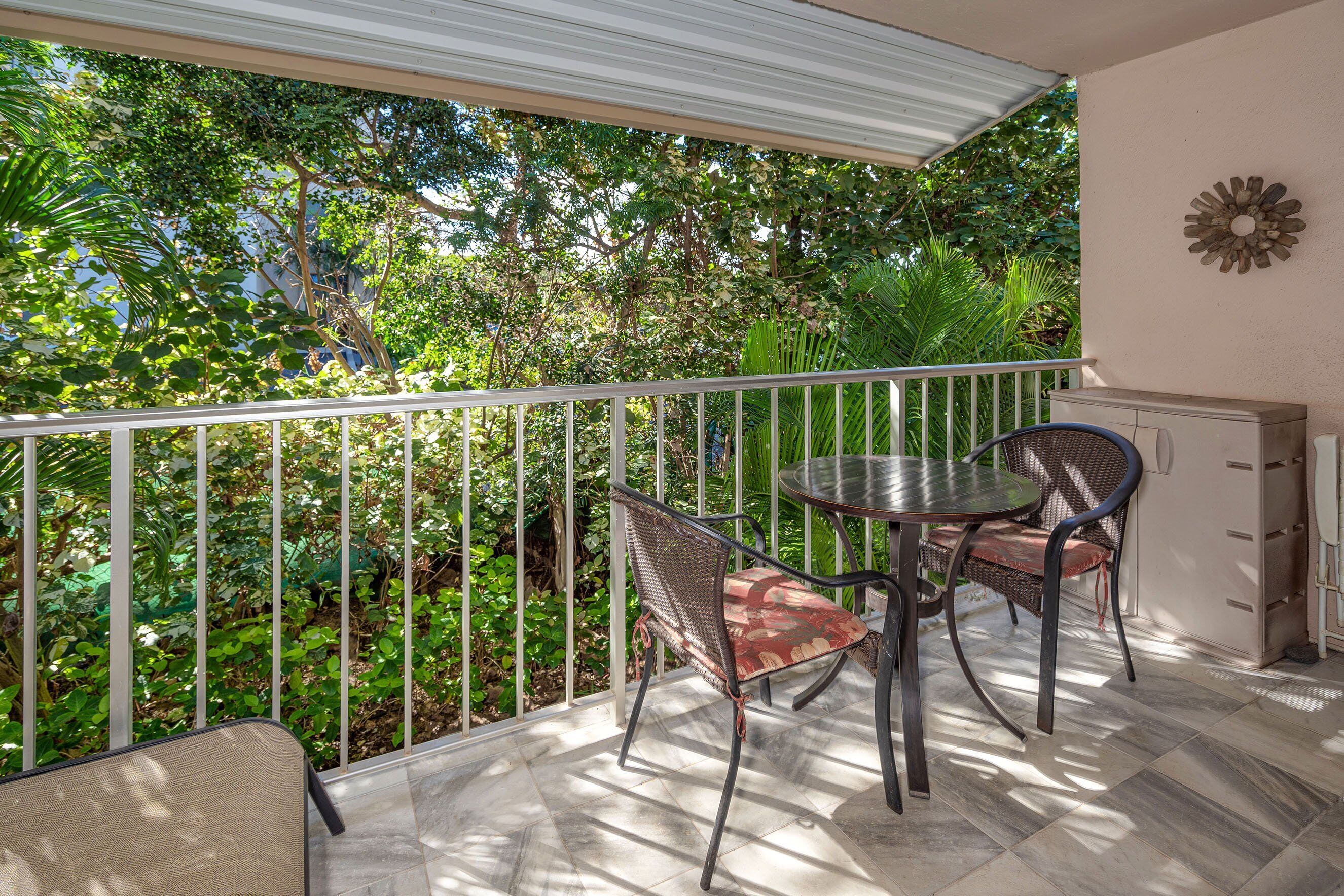 Un balcon agrémenté d’une table et de chaises, entouré d’une végétation luxuriante.