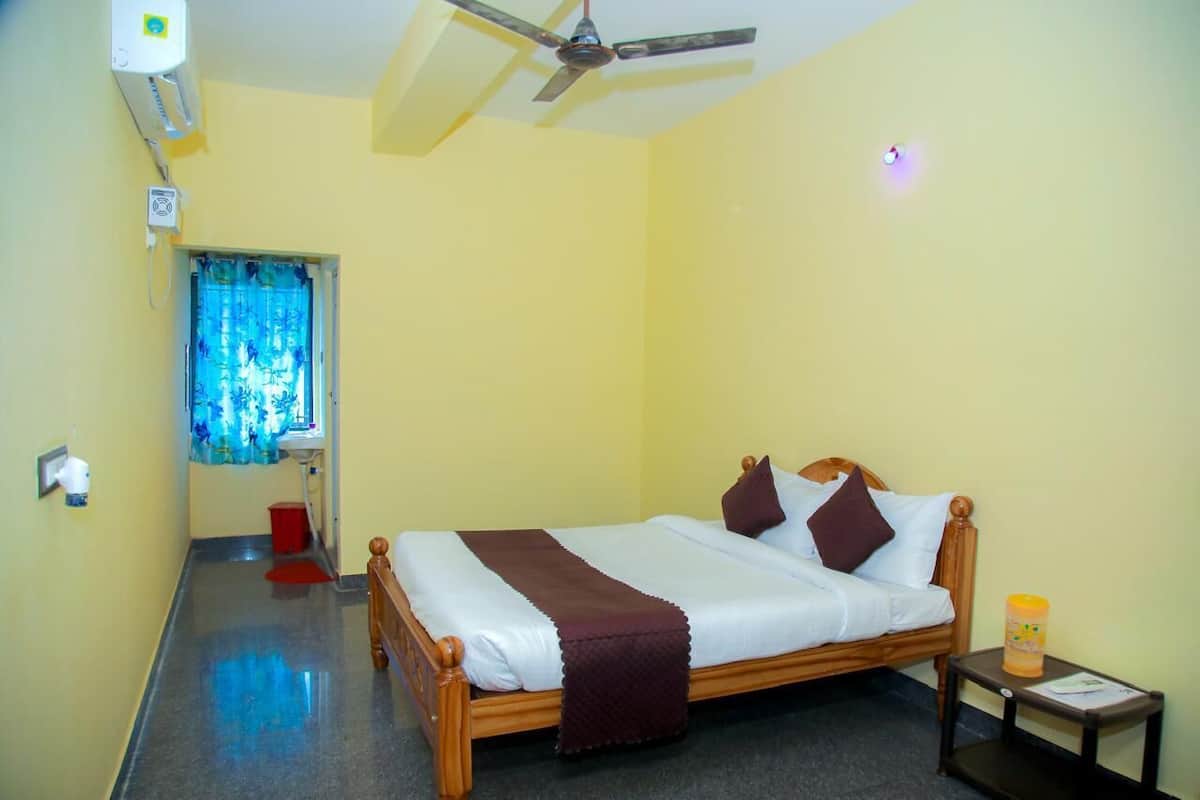 A bedroom with a bed, a ceiling fan, a window with curtains, a bedside table, and a nightstand.