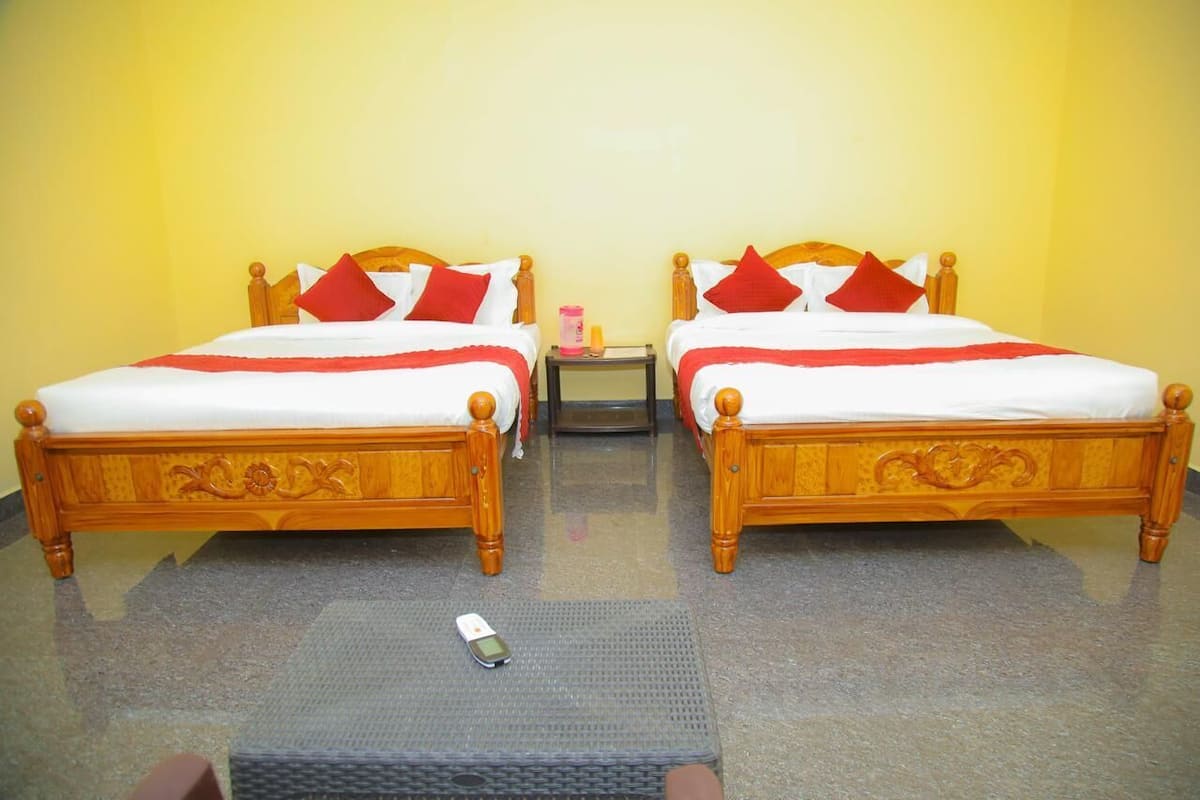 A room with two wooden beds, each with red and white bedding, and a small table with a remote control.