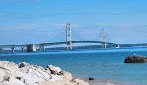 Eine große Hängebrücke über einem Gewässer mit felsiger Küstenlinie im Vordergrund.