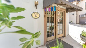 A building entrance with a door, a small awning, and a decorative hanging sign. - Charming Alamo Heights Studio (San Antonio)