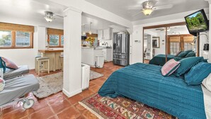 A spacious room with a large bed, a desk, and a kitchenette. - Charming Alamo Heights Studio (San Antonio)