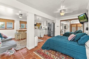 Una habitación amplia con una cama grande, un escritorio y una kitchenette.