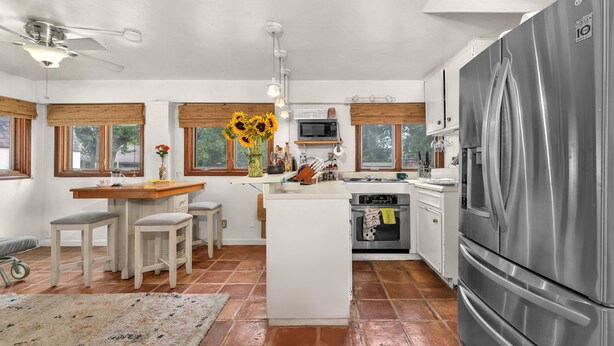 A modern kitchen with a central island, stainless steel appliances, and a dining area with stools. - Charming Alamo Heights Studio (San Antonio)