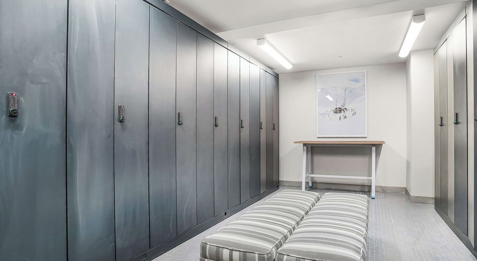 A hallway with metal lockers, a bench, and a table with a map on the wall.