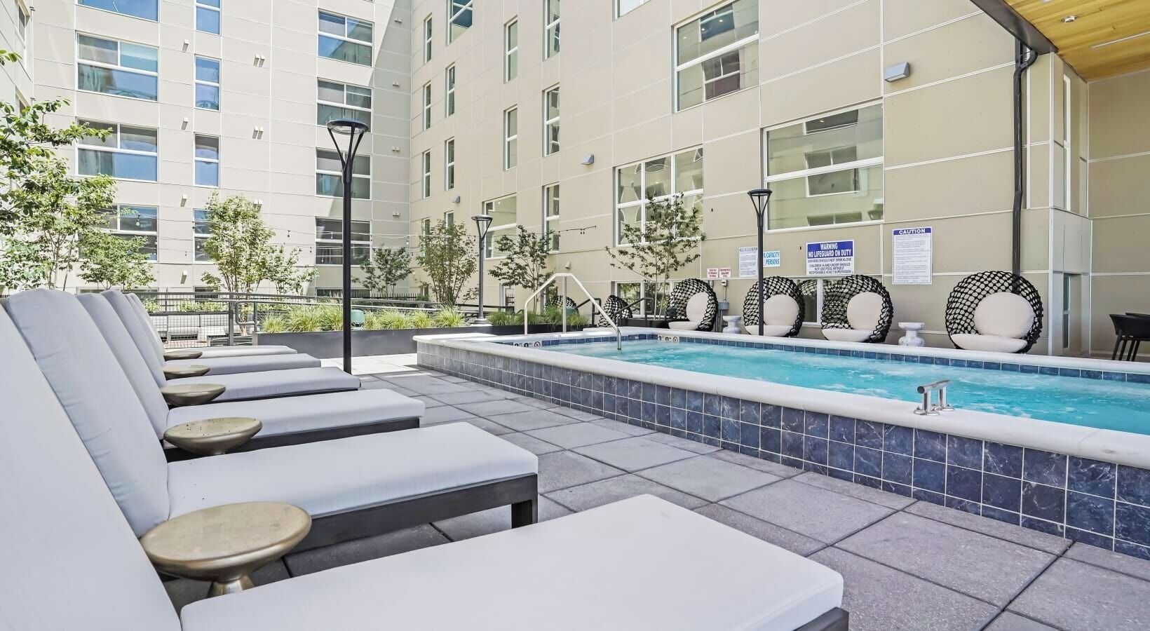 A rooftop pool area with lounge chairs and a swimming pool.