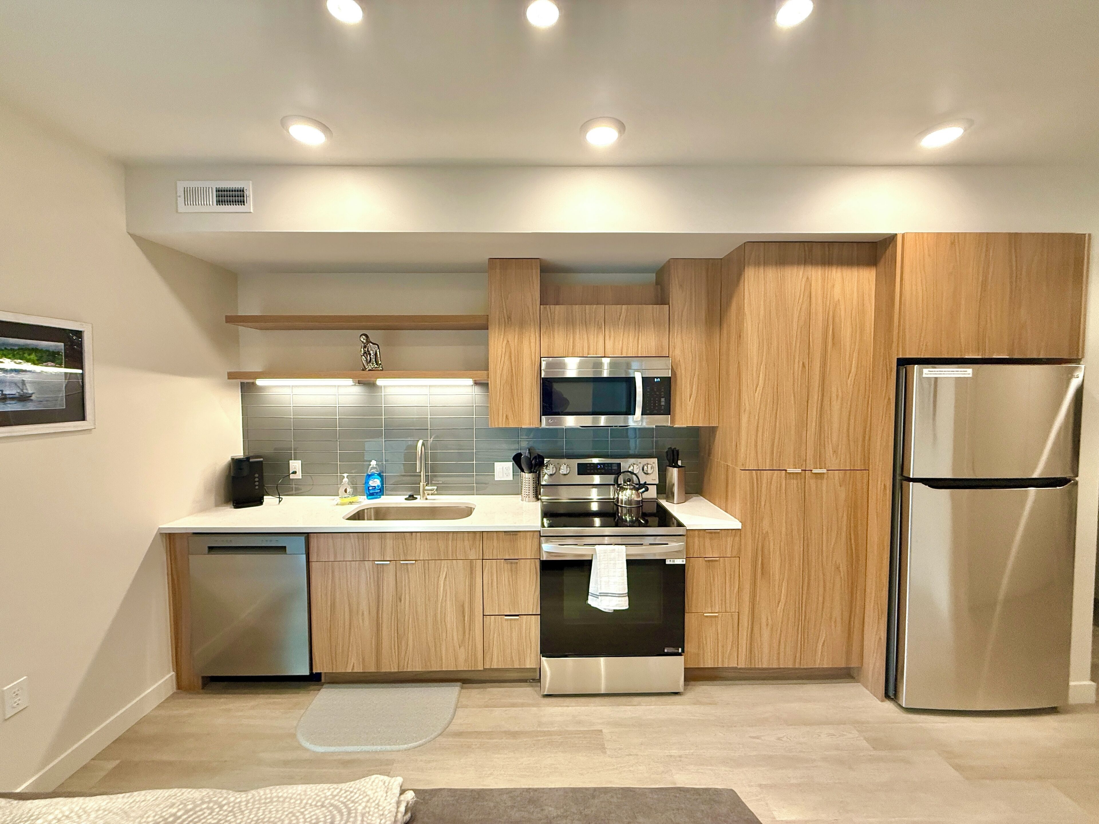 A modern kitchen with wooden cabinets, stainless steel appliances, and a built-in microwave.