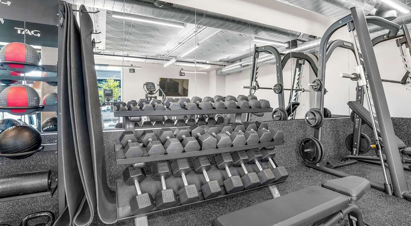 A gym with weightlifting equipment, including dumbbells and a squat rack.