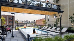 An outdoor swimming pool area with lounge chairs, a wooden canopy, and a view of the cityscape. - Ultra-Luxury Condo in Middle of Downtown (Salt Lake City)