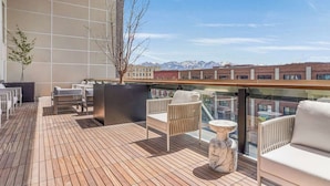 Une terrasse sur le toit avec un plancher en bois, des meubles en osier blanc et une table en marbre.