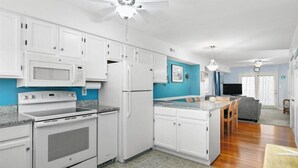 A kitchen with white cabinets, a microwave, a stove, and a refrigerator. - Adorable 2-bedroom townhome with outdoor POOL in Ocean City (Ocean City)