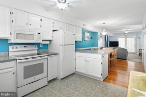 A kitchen with white cabinets, a microwave, a stove, and a refrigerator. - Adorable 2-bedroom townhome with outdoor POOL in Ocean City (Ocean City)