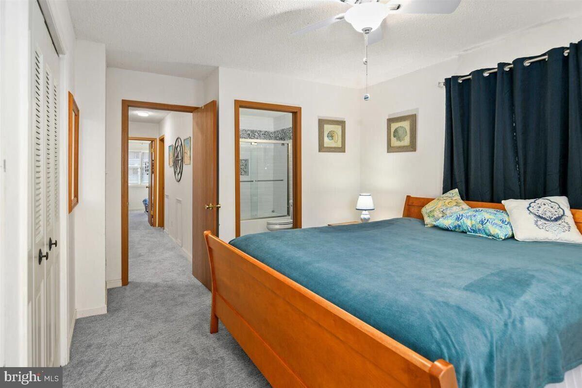 Ein Schlafzimmer mit einem hölzernen Bett, einem Deckenventilator und Blick auf einen Flur.