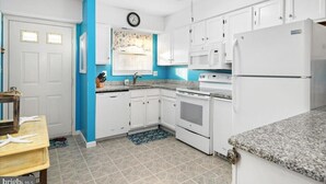 A kitchen with white cabinets, a microwave, an oven, and a refrigerator. - Adorable 2-bedroom townhome with outdoor POOL in Ocean City (Ocean City)