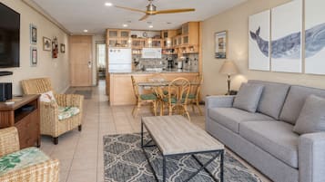 A modern living room with a grey sofa, wicker chairs, a wooden coffee table, and a television.