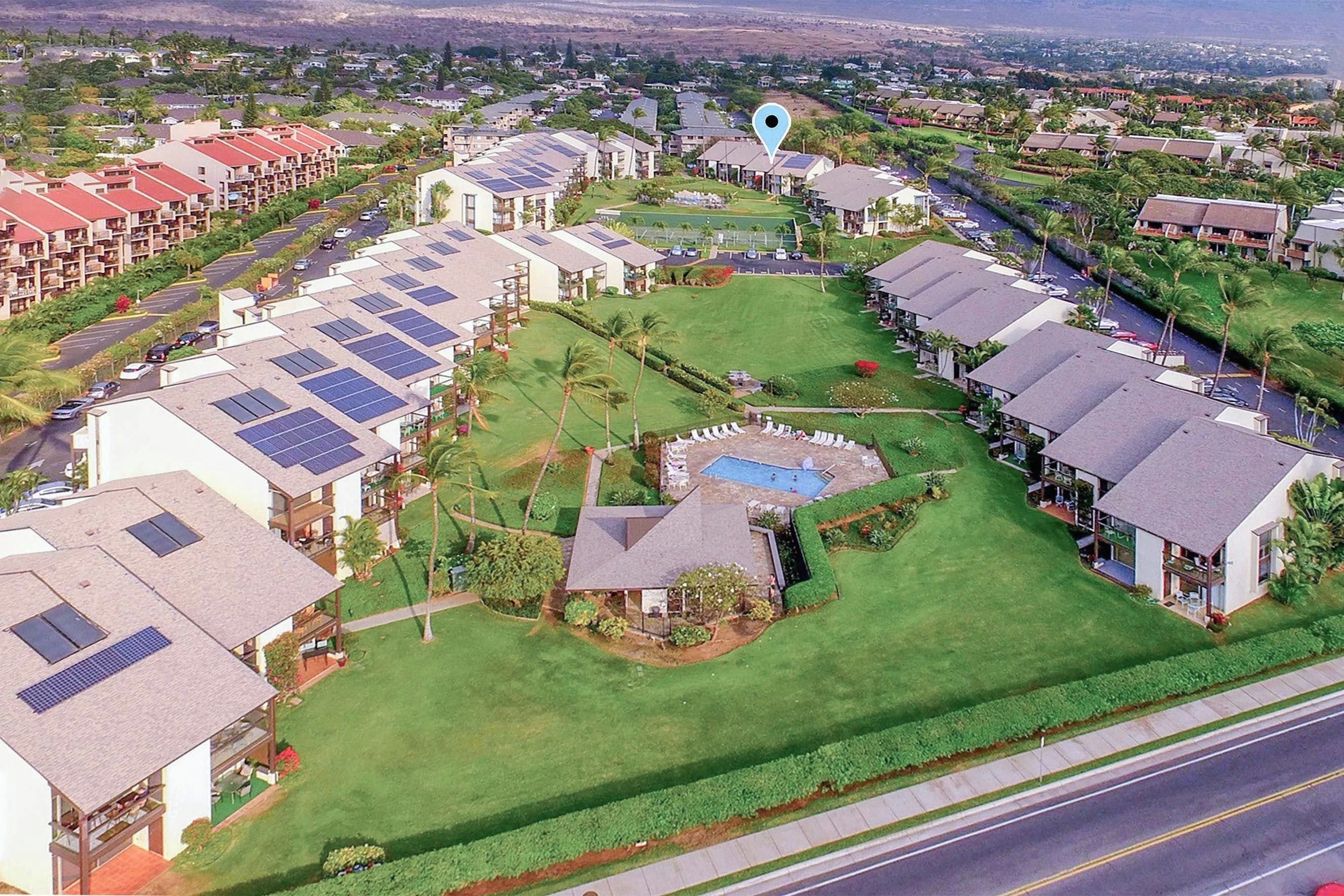 Un quartier résidentiel comprenant plusieurs maisons, une piscine et des panneaux solaires sur les toits.
