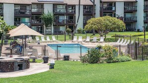 A swimming pool surrounded by a fence, with lounge chairs and a shaded area. - Hale Kamaole 150 - Great Ocean Views From Private Lanai, No Carpet, Split AC! (Kihei)