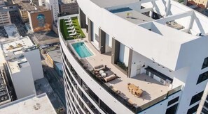 Eine Dachterrasse mit Pool, Sitzgelegenheiten im Freien und Blick auf die Stadtlandschaft.