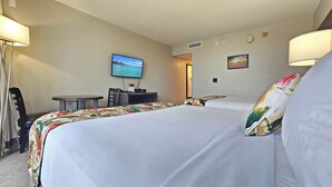 Ett hotellrum med två sängar, ett skrivbord, en TV och ett litet bord.