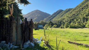 Une cabane rustique située dans un champ verdoyant, avec des montagnes en toile de fond.